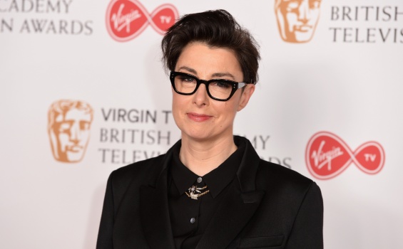 A professional woman with glasses dressed in a black suit, showcasing a polished appearance.